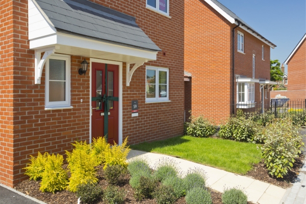 An empty street in a mostly complete new housing development, with houses sold before completion