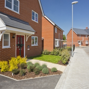 An empty street in a mostly complete new housing development, with houses sold before completion