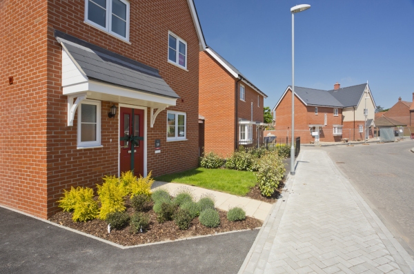 An empty street in a mostly complete new housing development, with houses sold before completion