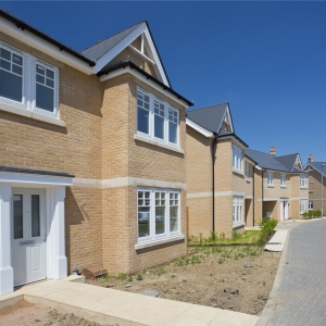 An empty street in a mostly complete new housing development, with houses sold before completion