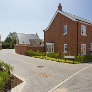 An empty street in a mostly complete new housing development, with houses sold before completion