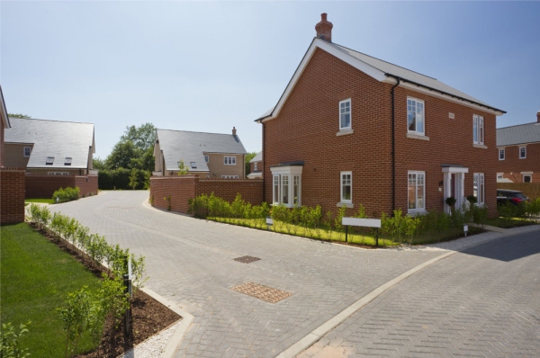 An empty street in a mostly complete new housing development, with houses sold before completion