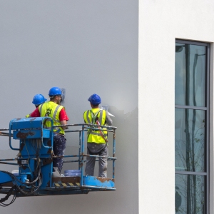 Three plasterers on a cherry picker plastering an office building