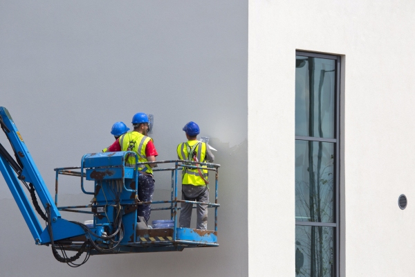 Three plasterers on a cherry picker plastering an office building