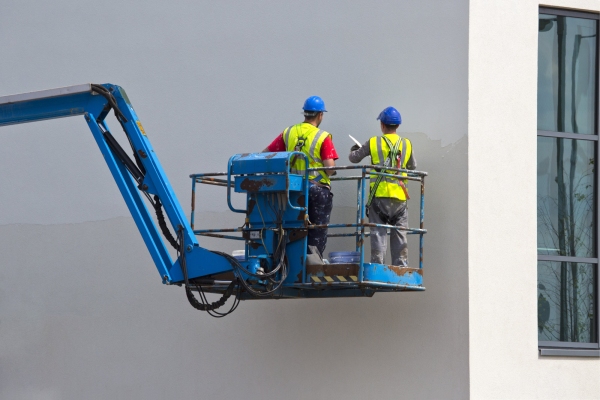 Two plasterers finishing off a wall on a lift platform