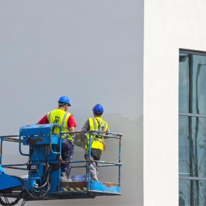 Two plasterers finishing off a new building from a cherry picker or lift platform