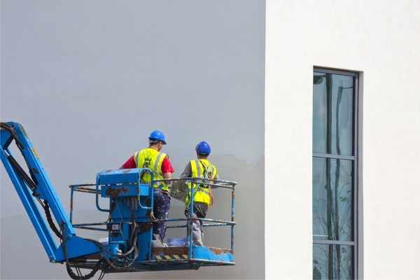 Two plasterers finishing off a new building from a cherry picker or lift platform