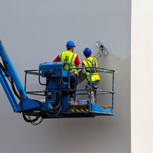 Two plasterers finishing a wall from a cherry picker