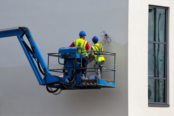 Two plasterers finishing a wall from a cherry picker