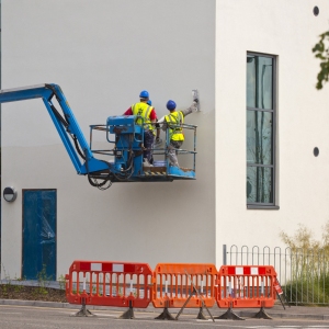 three plasterers working on a new office building from a lift platform