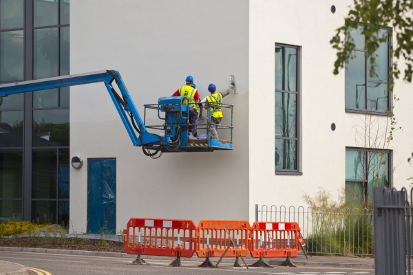 three plasterers working on a new office building from a lift platform