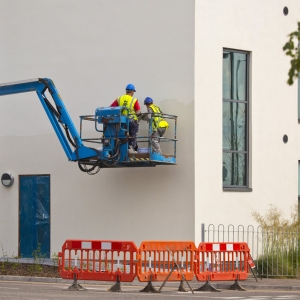 2 plasterers working on the wall of a new building from a cherry picker