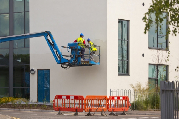 2 plasterers working on the wall of a new building from a cherry picker