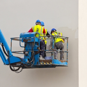 Three plasterers working on an office building from a cherry picker