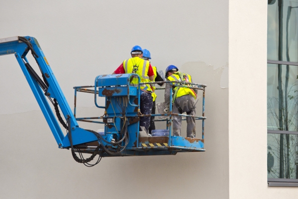 Three plasterers working on an office building from a cherry picker