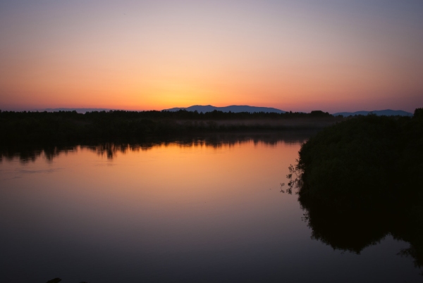 A river sunset with orange sky and reflections