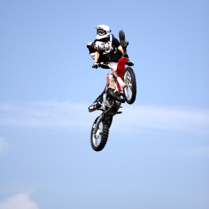 Motorcycle stunt rider flying high at a show