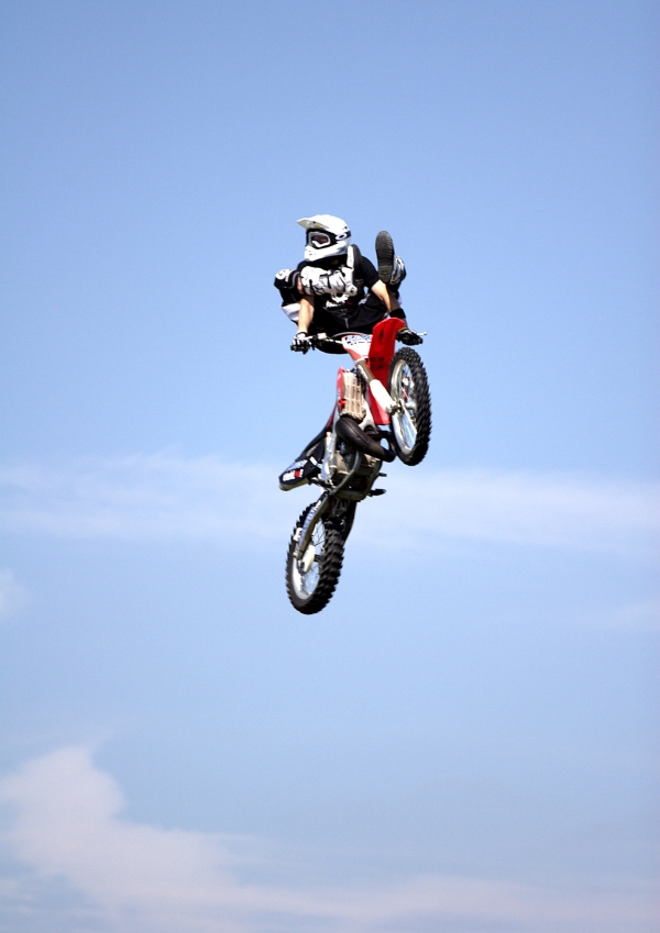 Motorcycle stunt rider flying high at a show