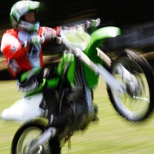 A motorcycle stunt rider doing a wheelie at a show, with motion blur