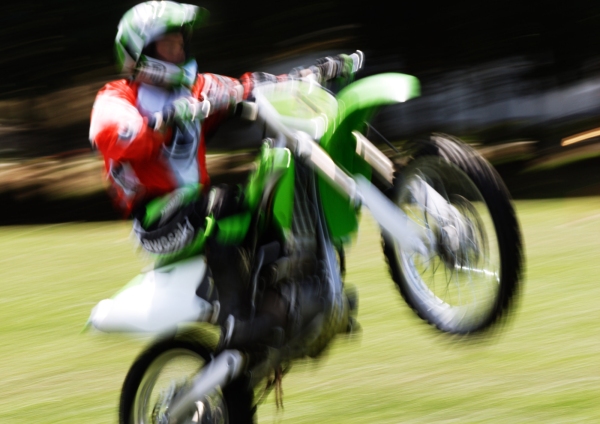 A motorcycle stunt rider doing a wheelie at a show, with motion blur