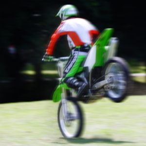 A stunt rider at a show doing a wheelie