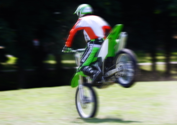 A stunt rider at a show doing a wheelie