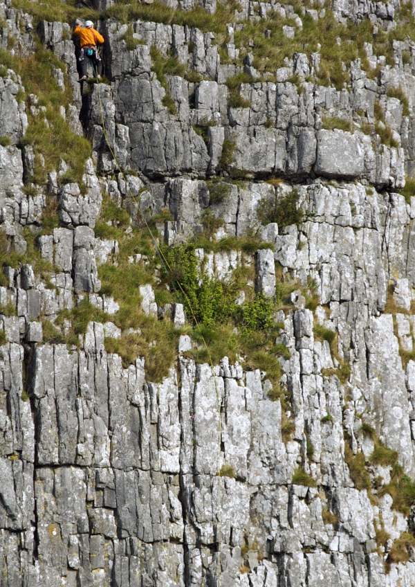 A rock climber seen from a distance on a rock face in the pennines