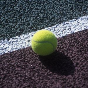 A new tennis ball on the line on a hard tennis court