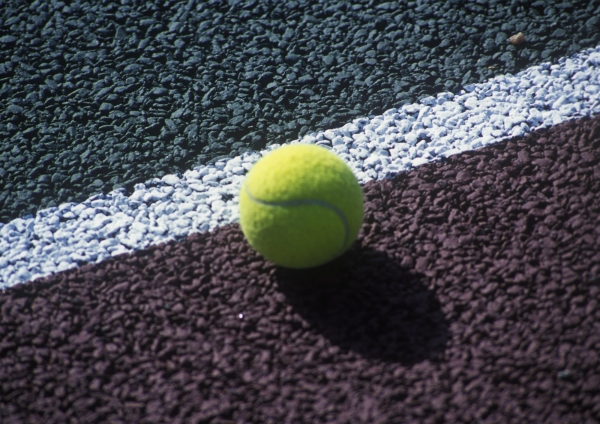 A new tennis ball on the line on a hard tennis court