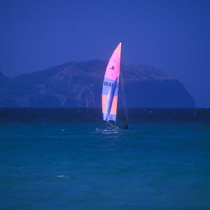 A colourful sailing dinghy on a sunny mediterranean sea