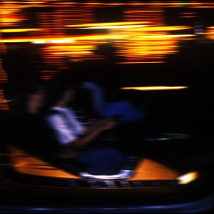 a blurred image of a fairground carousel at night, with bright lights