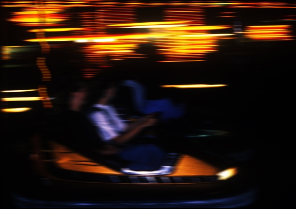 a blurred image of a fairground carousel at night, with bright lights