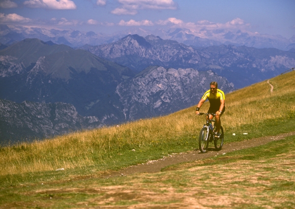 A cyclist on a mountain bike in a high alpine setting, with mountains in the background