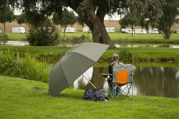 A carp fisherman waiting for a bite under an umbrella