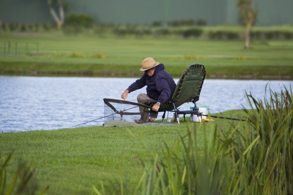 a coarse fisherman unhooking a small fish on an unhooking mat