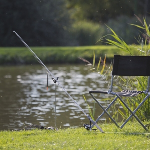 Coarse fishing gear on a lake or river bank, with rod, reel and float set up