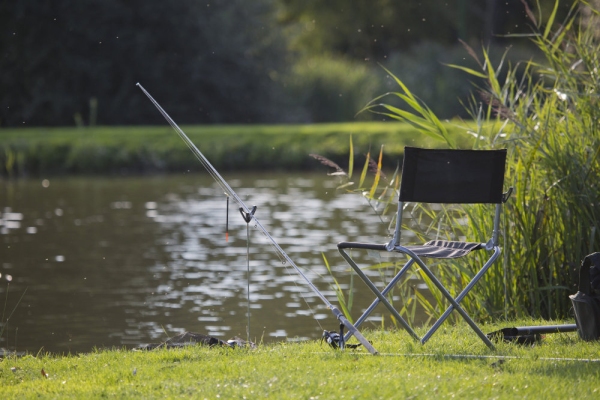 Coarse fishing gear on a lake or river bank, with rod, reel and float set up