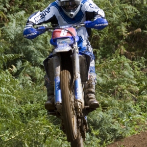 A motocross rider flying through the air on a high speed cross country race