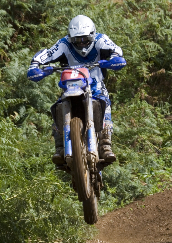 A motocross rider flying through the air on a high speed cross country race