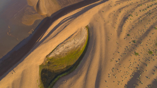 An aerial view of extensive sand dunes formed by wind and tide