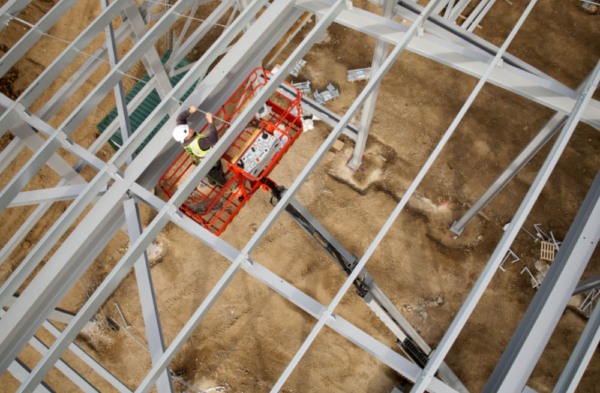 A steelworker on a lift platform on a large construction site