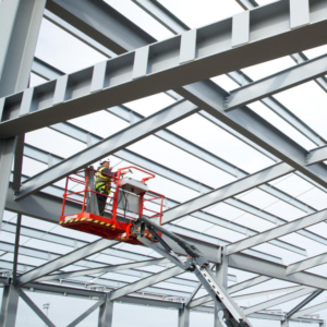 A steelworker on a lift platform on a large construction site