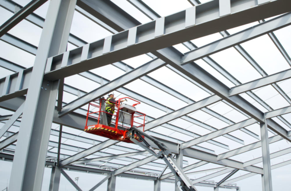 A steelworker on a lift platform on a large construction site