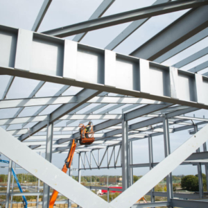 A steelworker on a lift platform on a large construction site