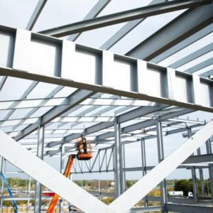 A steelworker on a lift platform on a large construction site