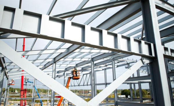 A steelworker on a lift platform on a large construction site