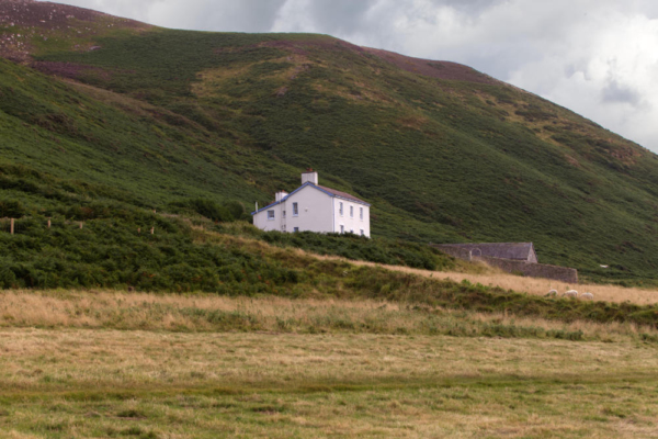 A white house set against a Welsh hillside on the Gower Peninsula