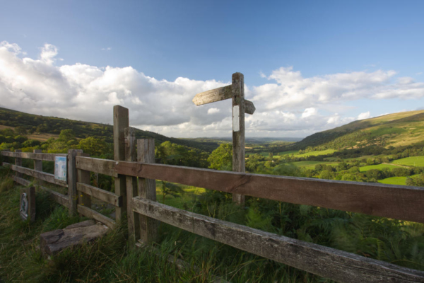 A view across the Brecon Beacons in South Wales with public footpath sign in the foreground