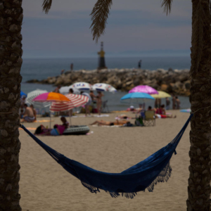 Holiday hammock strung between two palm trees on the beach at Portofino, Marbella in Southern Spain on the Costa del Sol